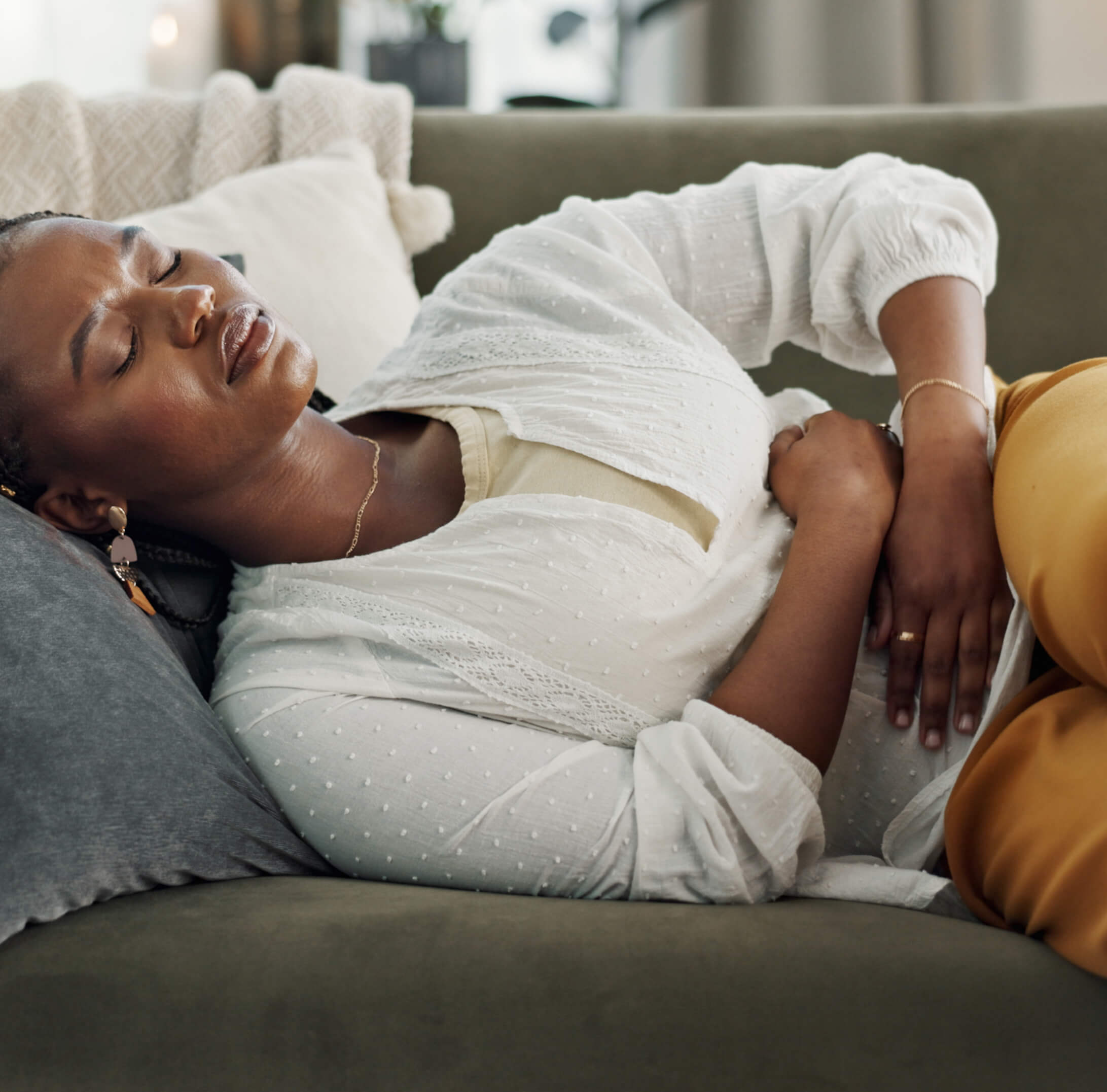Woman experiencing pelvic pain and discomfort while resting on a couch